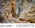 Climber on via ferrata trail, crossing a deep canyon. 130369378
