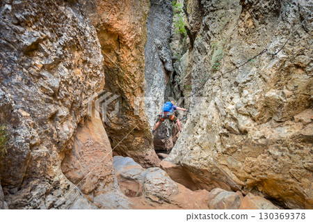 Climber on via ferrata trail, crossing a deep canyon. 130369378