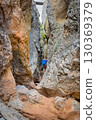 Climber on via ferrata trail, crossing a deep canyon. 130369379