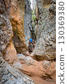 Climber on via ferrata trail, crossing a deep canyon. 130369380
