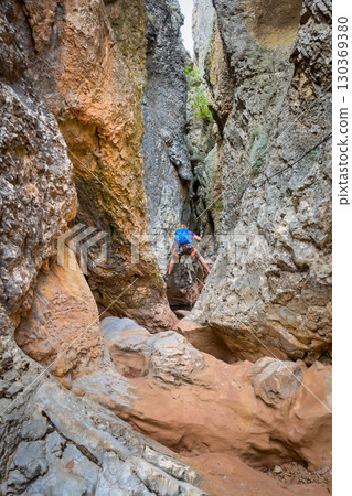 Climber on via ferrata trail, crossing a deep canyon. Climber on via ferrata trail, crossing a deep canyon. 130369380