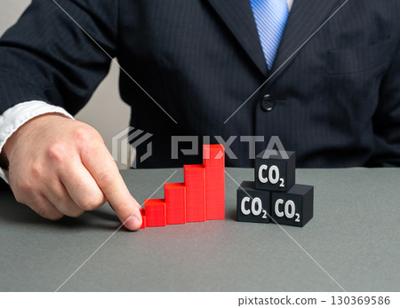 A graph of rising carbon dioxide emissions. A man studies the trend of rising pollution. Global warming, air quality decline, environmental research, ecological crisis, energy policy decisions 130369586