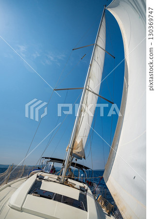 White sails filled with wind, seen from the bow of a sailing yacht near Croatia. Freedom, clean energy, adventure and mindful travel on the open sea. 130369747