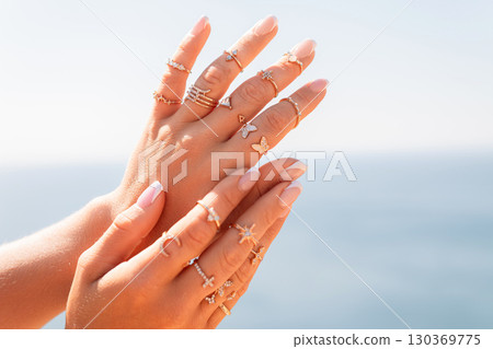 A woman is holding her hands up with a variety of rings on her fingers 130369775