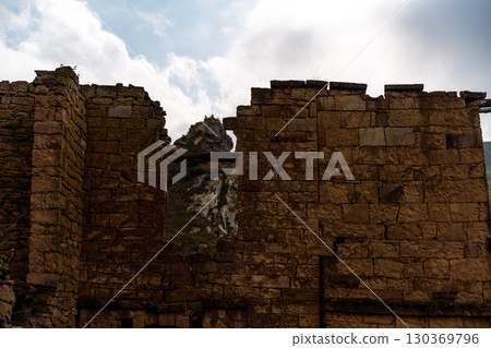 A stone building with a window and a mountain in the background A stone building with a window and a mountain in the background 130369796