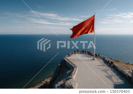 Ceremonial flag raising at coastal viewpoint with gathered crowd 130370403