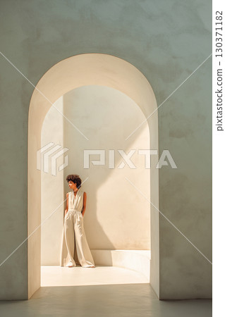 A woman stands in a doorway, looking out into a hallway 130371182