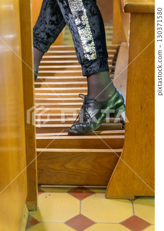 A close-up shot of a musician's foot pressing the pedals of a majestic, antique pipe organ 130371580