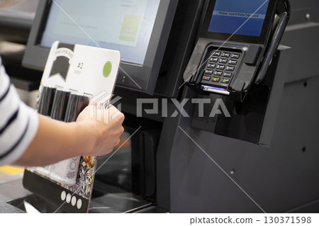 A woman's hands using a self-checkout at an American supermarket 130371598