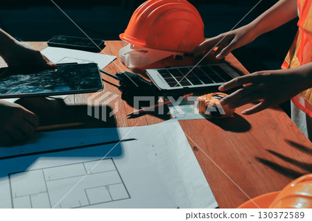 Closeup of team of industrial engineers meeting analyze machinery blueprints consult project on table in manufacturing factory. Working in manufacturing plant or production plant. 130372589