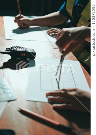 Closeup of team of industrial engineers meeting analyze machinery blueprints consult project on table in manufacturing factory. Working in manufacturing plant or production plant. Closeup of team of industrial engineers meeting analyze machinery blueprints consult project on table in manufacturing factory. Working in manufacturing plant or production plant. 130372596