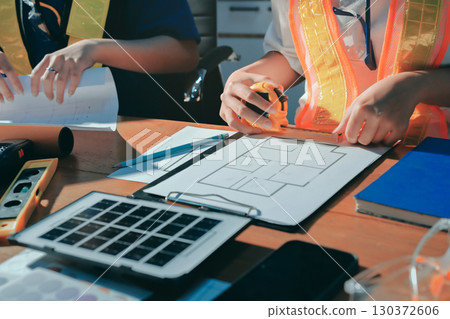 Closeup of team of industrial engineers meeting analyze machinery blueprints consult project on table in manufacturing factory. Working in manufacturing plant or production plant. Closeup of team of industrial engineers meeting analyze machinery blueprints consult project on table in manufacturing factory. Working in manufacturing plant or production plant. 130372606