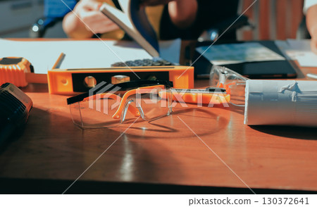 Closeup of team of industrial engineers meeting analyze machinery blueprints consult project on table in manufacturing factory. Working in manufacturing plant or production plant. 130372641