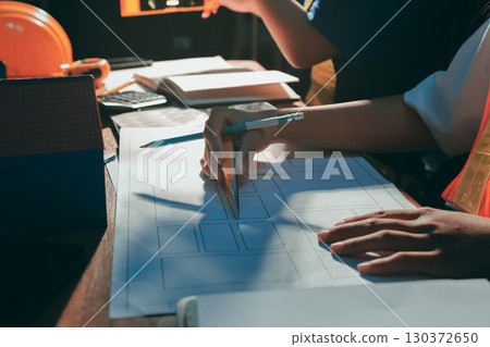 Closeup of team of industrial engineers meeting analyze machinery blueprints consult project on table in manufacturing factory. Working in manufacturing plant or production plant. Closeup of team of industrial engineers meeting analyze machinery blueprints consult project on table in manufacturing factory. Working in manufacturing plant or production plant. 130372650