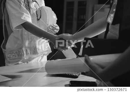 Closeup of team of industrial engineers meeting analyze machinery blueprints consult project on table in manufacturing factory. Working in manufacturing plant or production plant. 130372671