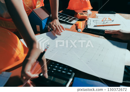 Closeup of team of industrial engineers meeting analyze machinery blueprints consult project on table in manufacturing factory. Working in manufacturing plant or production plant. 130372672