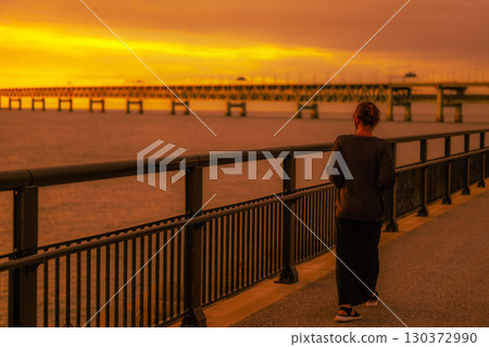 一位女士在黃昏時分沿著海濱散步 一位女士在黃昏時分沿著海濱散步 130372990