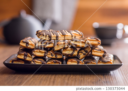 Sfogliatine glassate with chocolate. Italian crispy dessert on plate on wooden table. 130373044