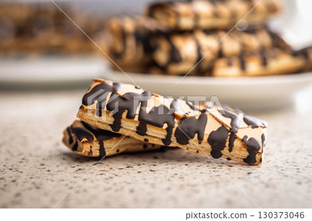 Sfogliatine glassate with chocolate. Italian crispy dessert on kitchen table. 130373046