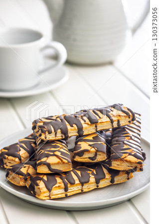 Sfogliatine glassate with chocolate. Italian crispy dessert on plate on white table. 130373056