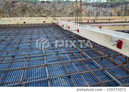 Steel reinforcement is placed in wooden molds and formwork on a construction site 130373071
