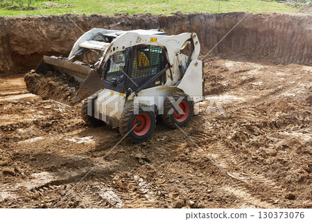 Heavy machinery moves dirt at a construction site with a clear focus on ground leveling and preparation for building Heavy machinery moves dirt at a construction site with a clear focus on ground leveling and preparation for building 130373076