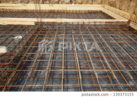 Steel reinforcement is placed in wooden molds and formwork on a construction site 130373155