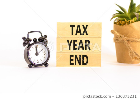 Tax year end symbol. Concept words Tax year end on beautiful wooden blocks. Beautiful white background. Black alarm clock. Business tax year end concept. Copy space. 130373231