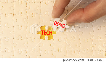 Tech demo symbol. Concept word Tech demo on beautiful white puzzles. Businessman's hand. Beautiful yellow paper background. Business tech demo concept. Copy space. Tech demo symbol. Concept word Tech demo on beautiful white puzzles. Businessman's hand. Beautiful yellow paper background. Business tech demo concept. Copy space. 130373363