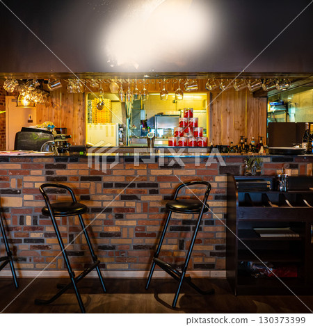 Half-lighted hall in a loft style restaurant open kitchen background. Half-lighted hall in a loft style restaurant open kitchen background. 130373399