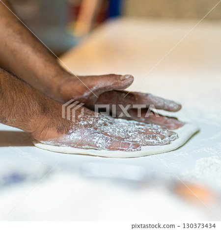 Chef's hands spraying flour over the dough. Kneading dough. chef kitchen dough 130373434