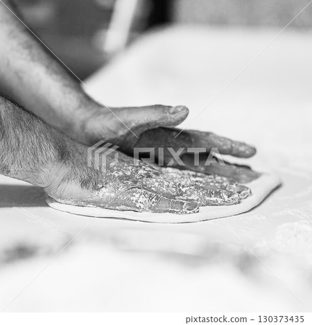 Chef's hands spraying flour over the dough. Kneading dough. chef kitchen dough 130373435