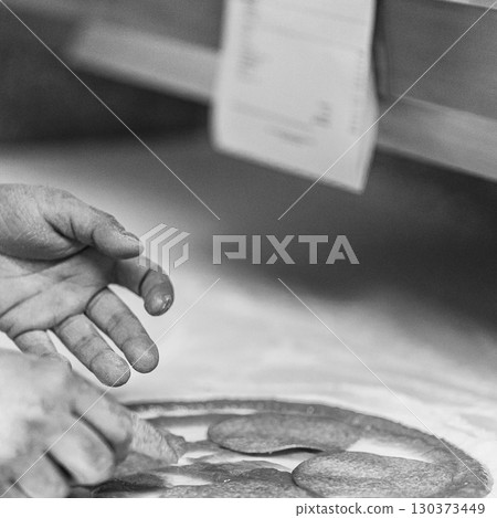 Hands preparing a pizza putting salami on pizza Hands preparing a pizza putting salami on pizza 130373449