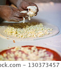 Hands preparing a pizza putting cheese mozzarella on pizza 130373457