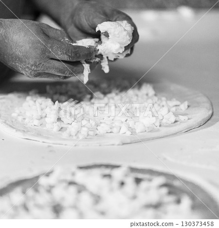 Hands preparing a pizza putting cheese mozzarella on pizza Hands preparing a pizza putting cheese mozzarella on pizza 130373458