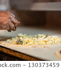 Hands preparing a pizza putting cheese mozzarella on pizza 130373459