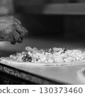 Hands preparing a pizza putting cheese mozzarella on pizza 130373460