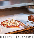 Hands preparing a pizza putting cheese mozzarella on pizza 130373461