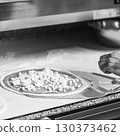 Hands preparing a pizza putting cheese mozzarella on pizza 130373462