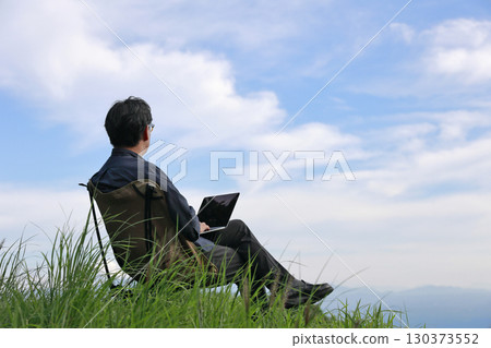 The future of work: A man using his laptop in the grass 130373552