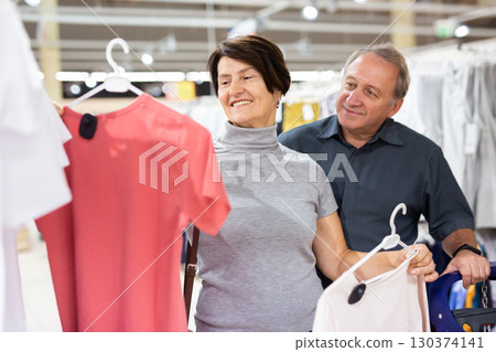 Mature couple choosing t-shirts in clothes department in grocery store Mature couple choosing t-shirts in clothes department in grocery store 130374141