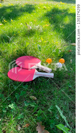 Table tennis rackets and balls on green grass, outdoor leisure Table tennis rackets and balls on green grass, outdoor leisure 130374299