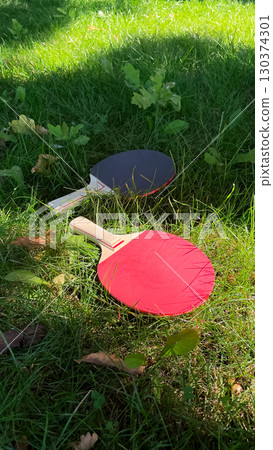 Table tennis rackets and balls on green grass, outdoor leisure 130374301