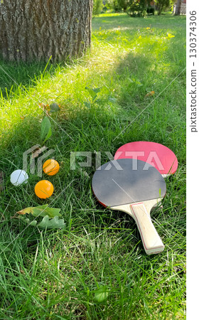 Table tennis rackets and balls on green grass, outdoor leisure Table tennis rackets and balls on green grass, outdoor leisure 130374306