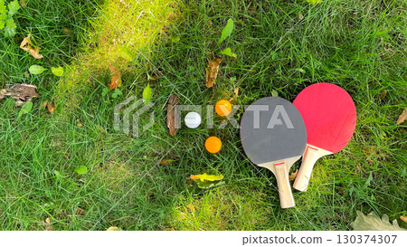 Table tennis rackets and balls on green grass, outdoor leisure Table tennis rackets and balls on green grass, outdoor leisure 130374307