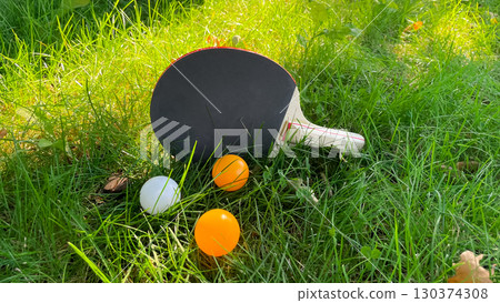 Table tennis rackets and balls on green grass, outdoor leisure Table tennis rackets and balls on green grass, outdoor leisure 130374308