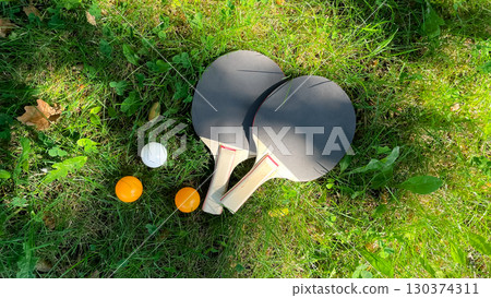 Table tennis rackets and balls on green grass, outdoor leisure Table tennis rackets and balls on green grass, outdoor leisure 130374311