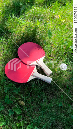 Table tennis rackets and balls on green grass, outdoor leisure Table tennis rackets and balls on green grass, outdoor leisure 130374314