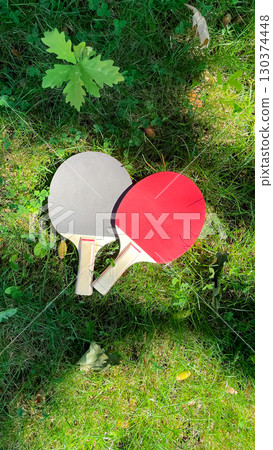 Table tennis rackets and balls on green grass, outdoor leisure 130374448