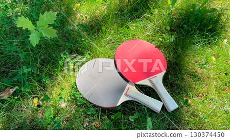 Table tennis rackets and balls on green grass, outdoor leisure Table tennis rackets and balls on green grass, outdoor leisure 130374450